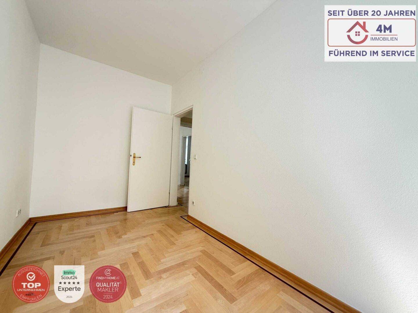 Ruhiges Zimmer mit Fischgrätparkett und einer Tür, die zu einem weiteren Raum führt.