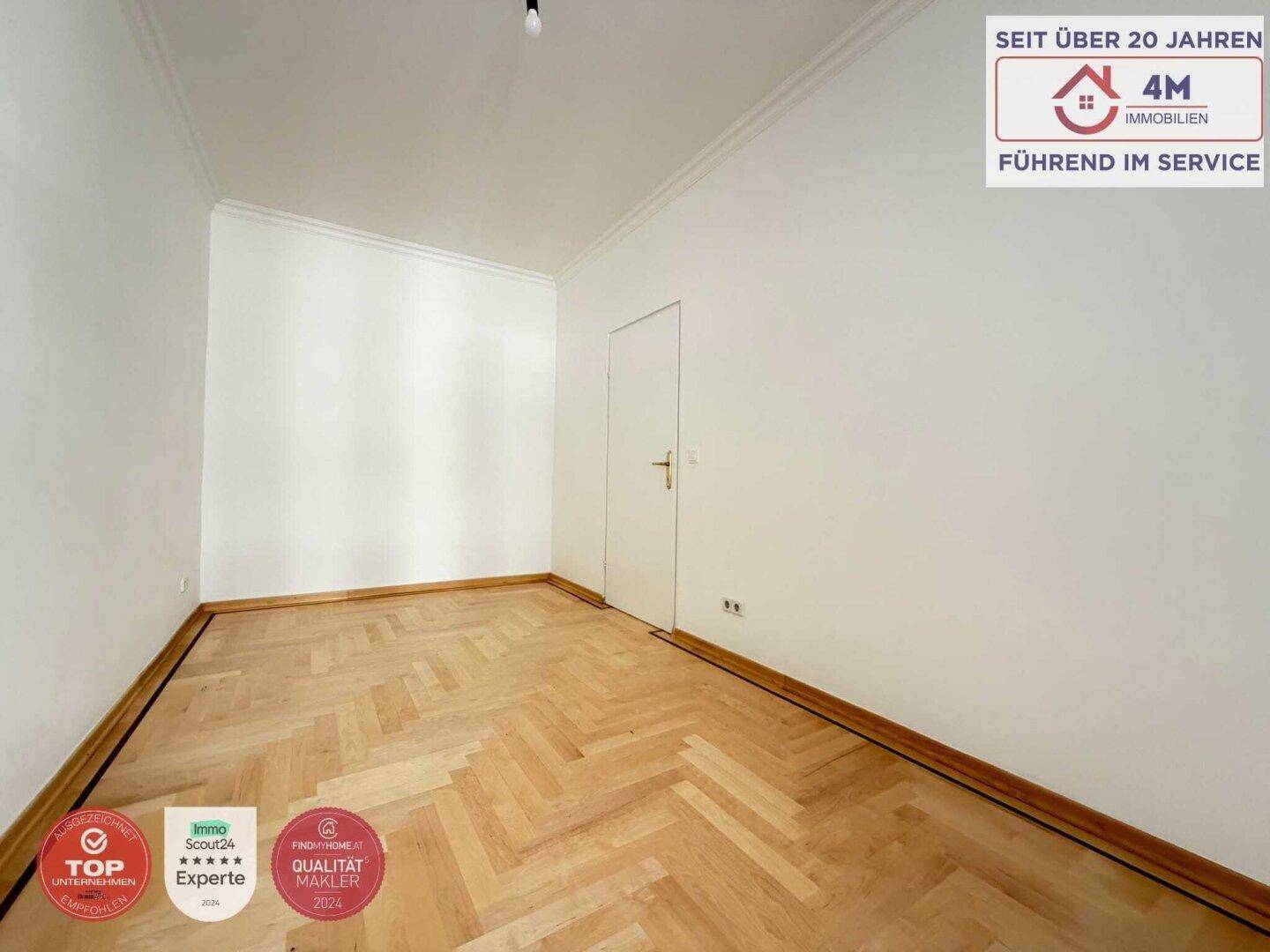 Gemütliches Zimmer mit Fischgrätparkett und einer schlichten weißen Tür.