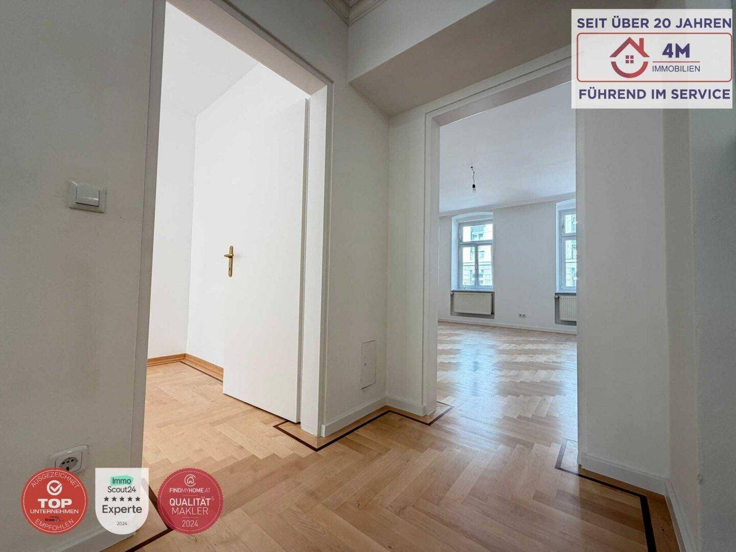 Heller Flur mit Fischgrätparkett, der zu verschiedenen Zimmern der Wohnung führt.