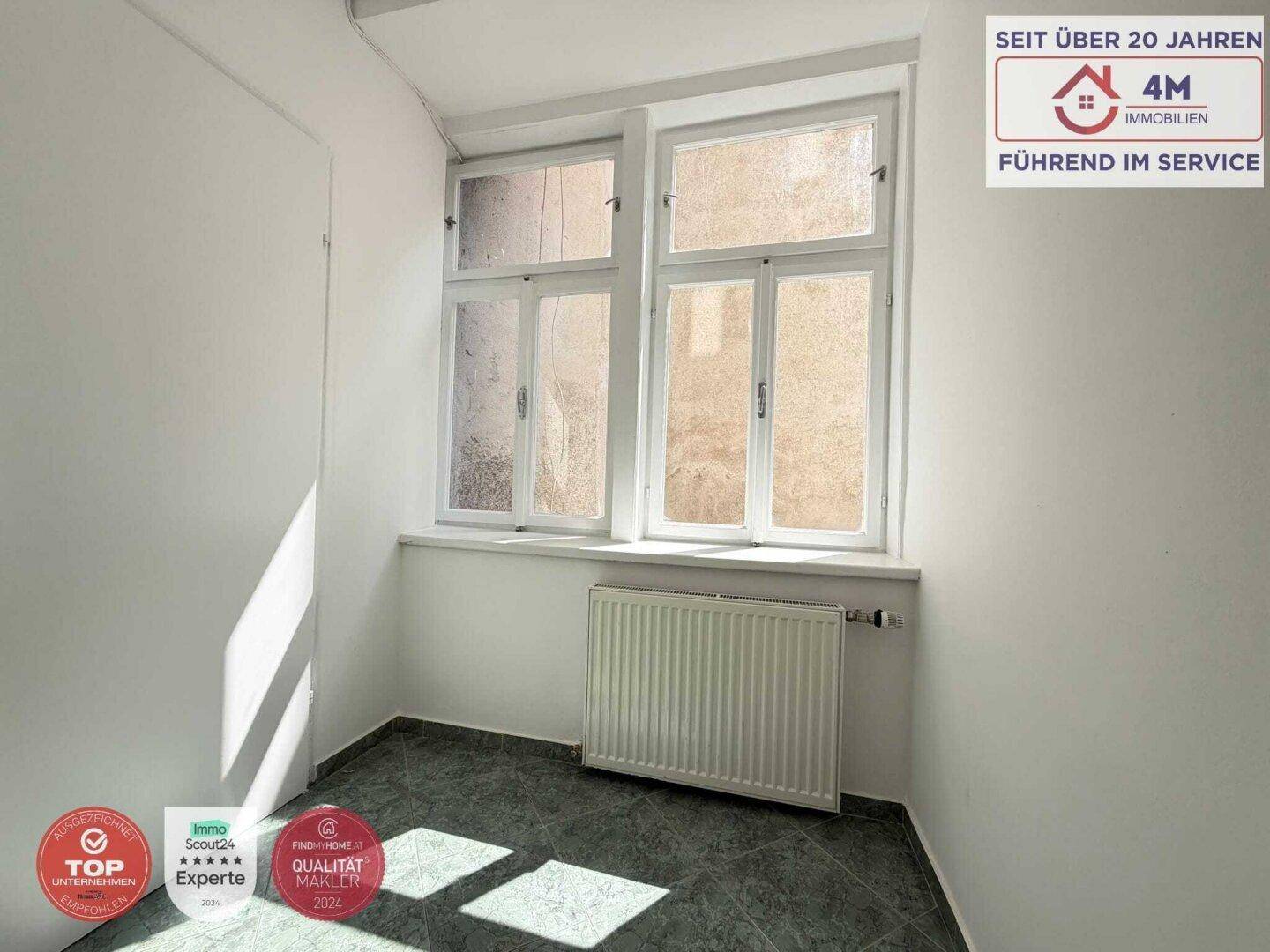 Kleiner Raum mit Fenster und dunklem Fliesenboden, ideal als Abstellraum.