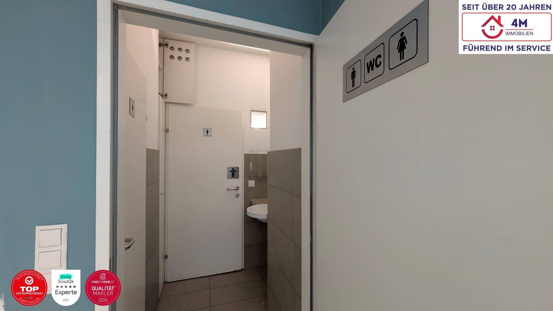 Eingang zu einem funktionalen WC-Bereich mit gefliesten Wänden und einer Wandtoilette.