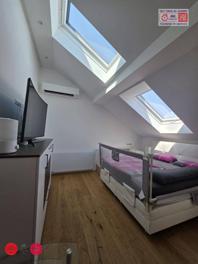 Schlafzimmer im Dachgeschoss mit Dachfenstern, Laminatboden und Klimaanlage.