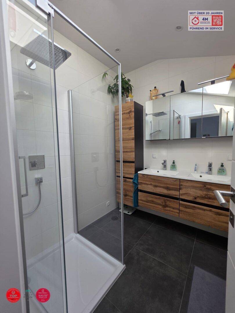 Modernes Badezimmer mit begehbarer Dusche, Doppelwaschbecken und Holzunterschränken.