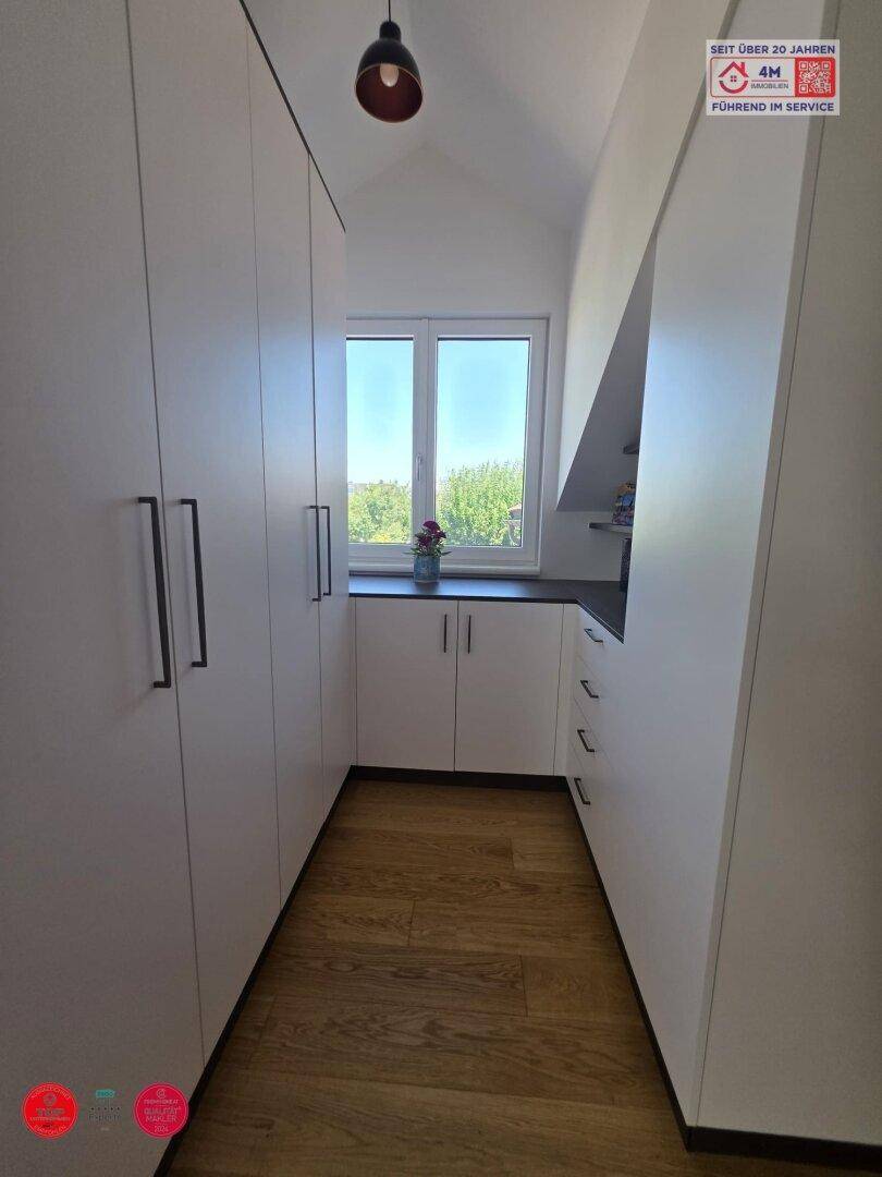 Heller Flur mit Einbauschränken, Laminatboden und Fenster am Ende.