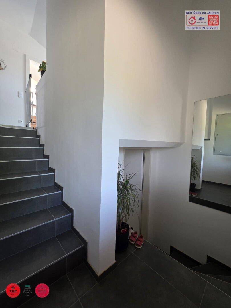 Treppenhaus mit dunklen Fliesenstufen und einem Spiegel an der Wand.