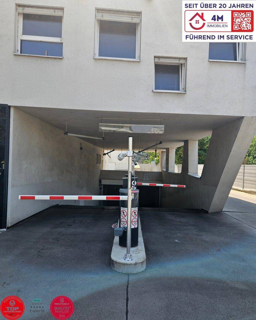 Eingangsbereich einer Tiefgarage mit Schranke und Gebäudefassade.