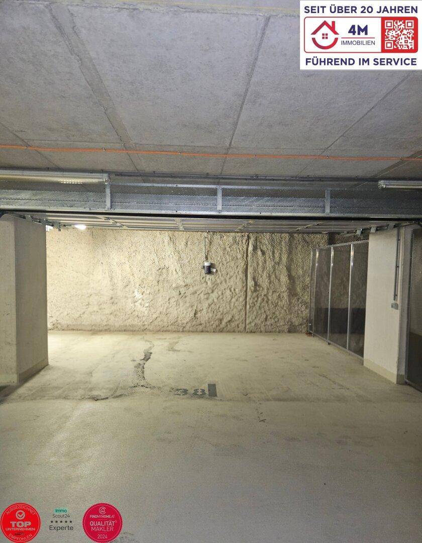 Breiter Stellplatz in der Tiefgarage mit rauer Felswand und Betonboden.