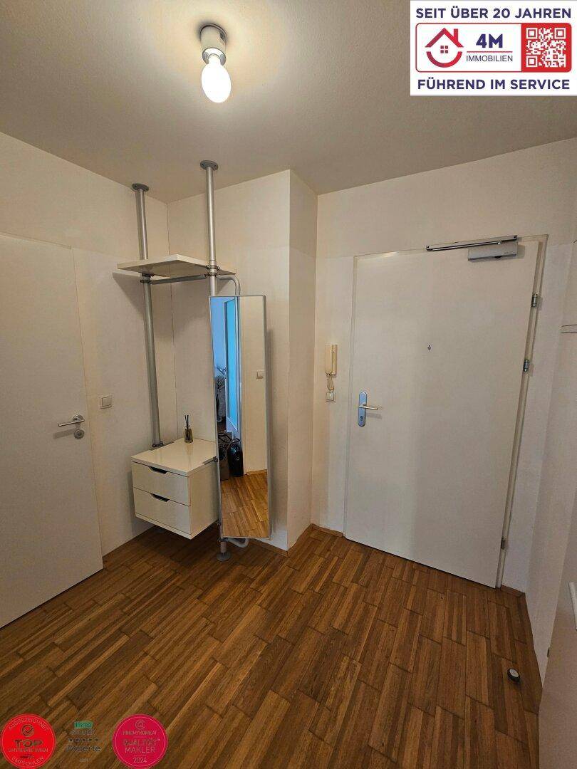 Eingangsbereich mit Garderobe, Spiegel und Parkettboden, der zu den weiteren Räumen führt.