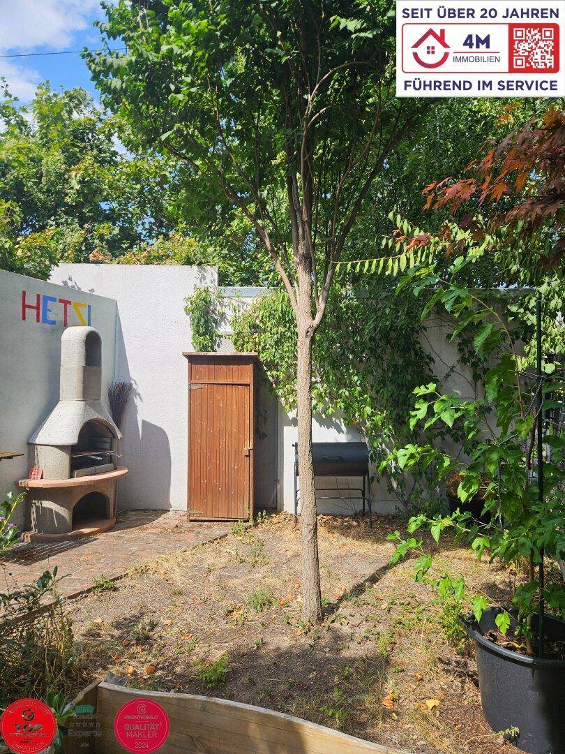 Hinterhofgarten mit Grillplatz, Gartenhaus und üppiger Vegetation.
