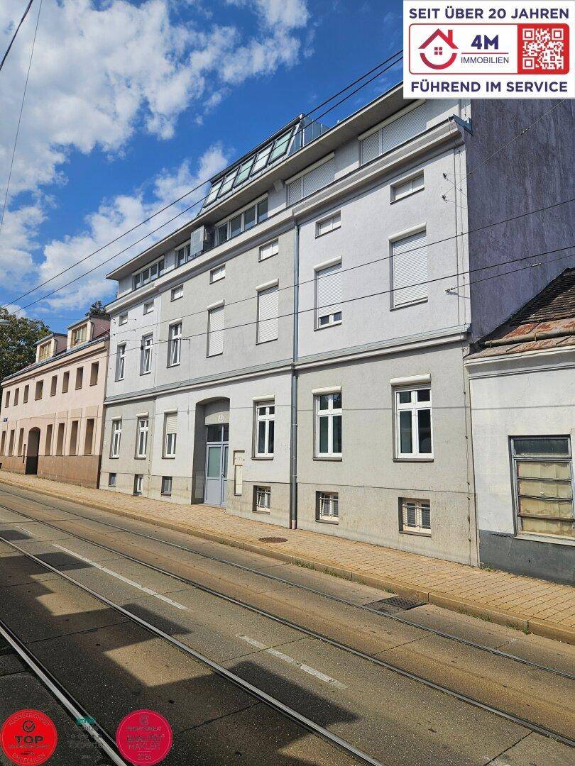 Mehrfamilienhaus mit moderner Fassade und Dachgauben an einer städtischen Straße.