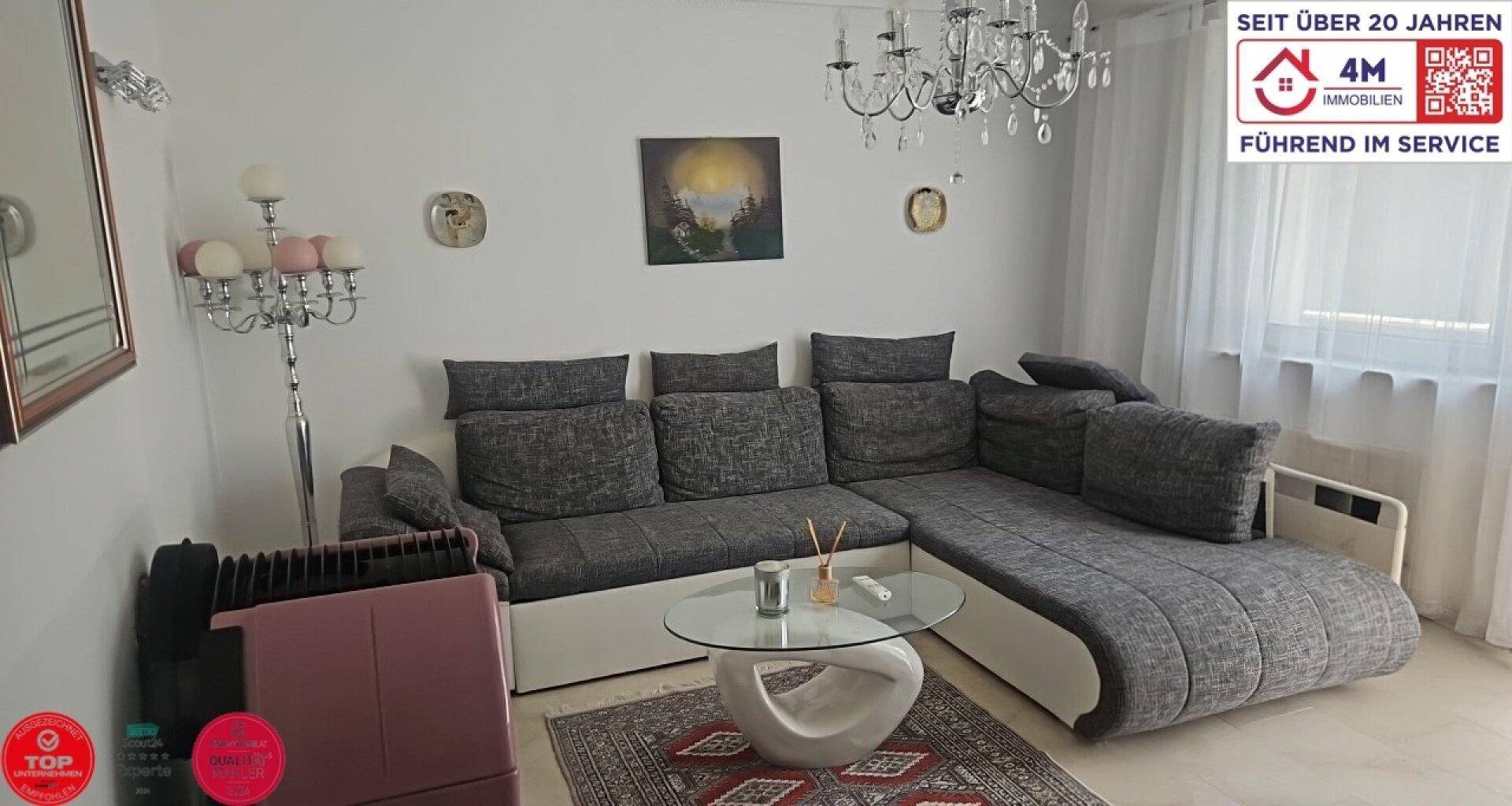 Gemütliches Wohnzimmer mit großem Ecksofa, Kronleuchter und hellem Ambiente.