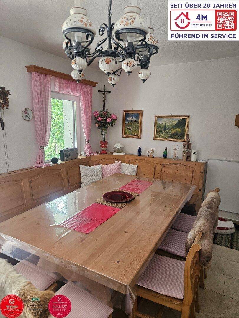 Traditioneller Essbereich mit großer Holzbank, Esstisch und rustikalem Kronleuchter.