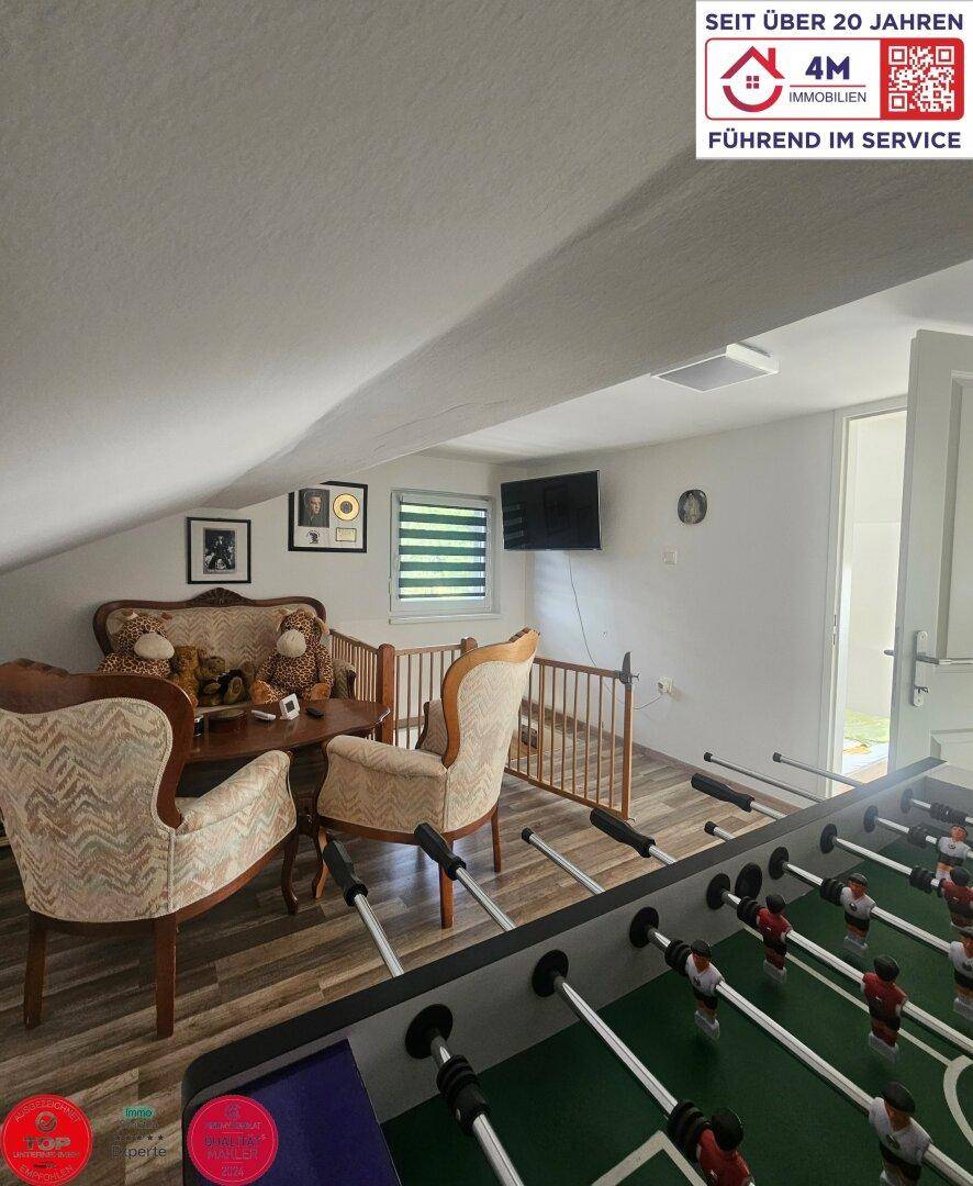 Dachgeschoss-Wohnraum mit Tischfußball, Sitzgelegenheiten und schrägen Decken.