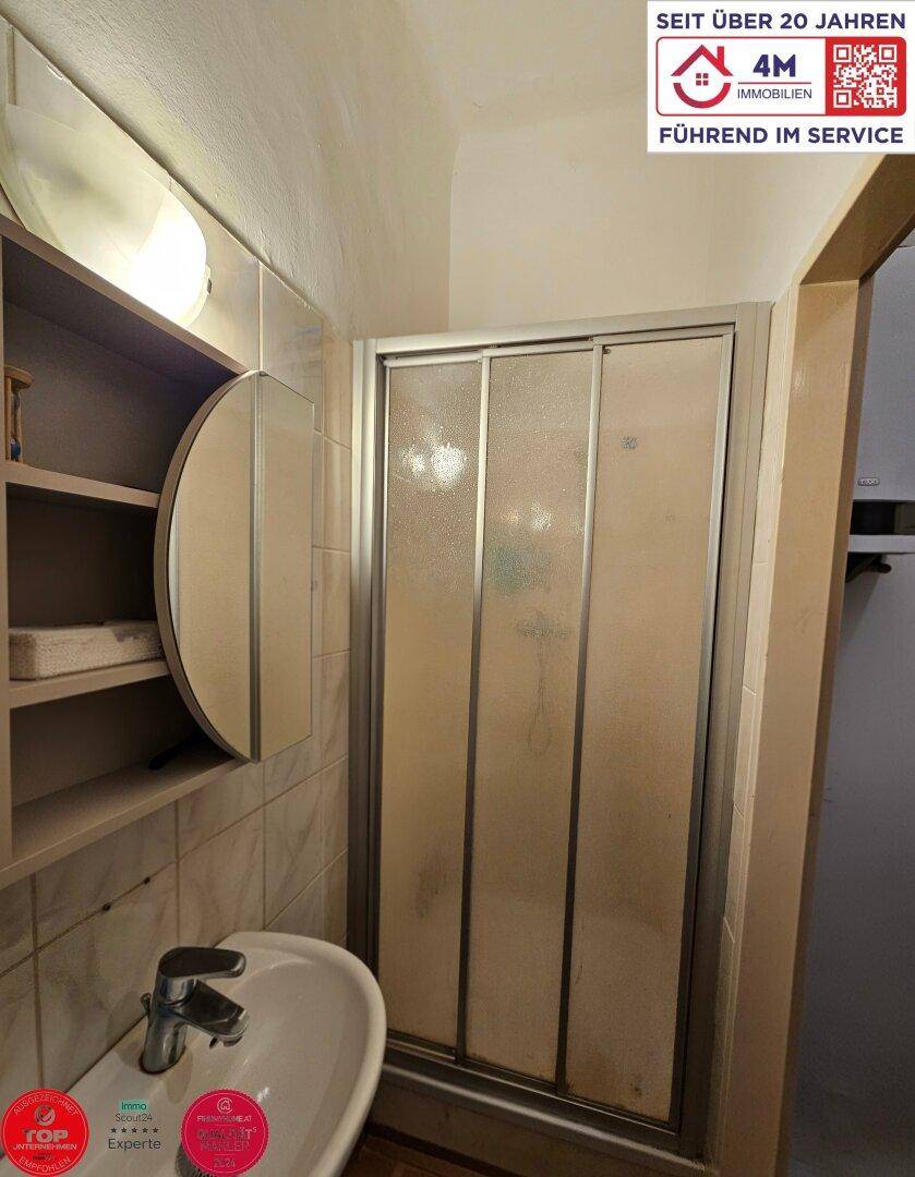 Badezimmer mit Duschkabine, Waschbecken und Spiegelschrank.