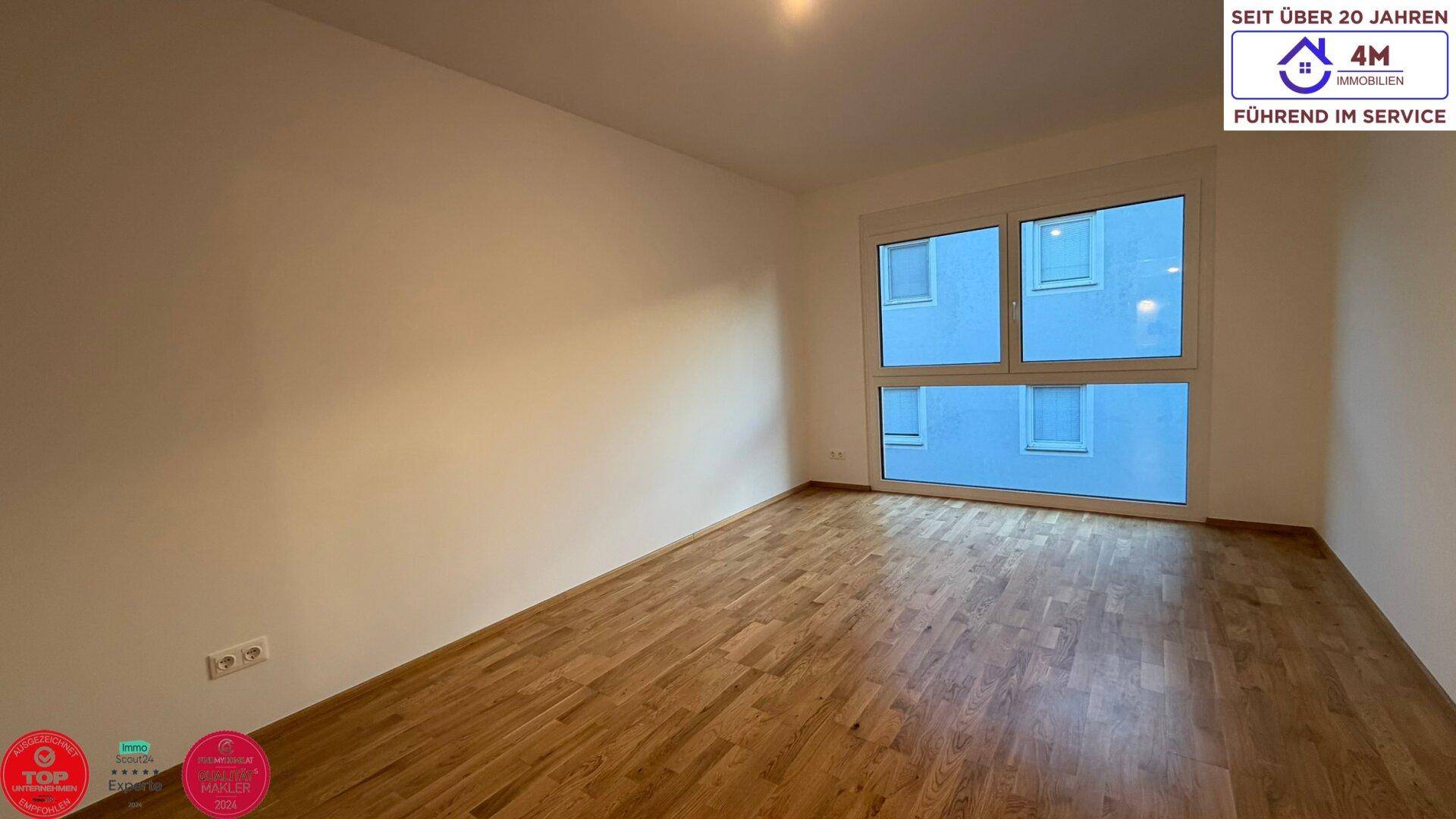 Helles Schlafzimmer mit Parkettboden und großen Fenstern, bietet eine angenehme Wohnatmosphäre.