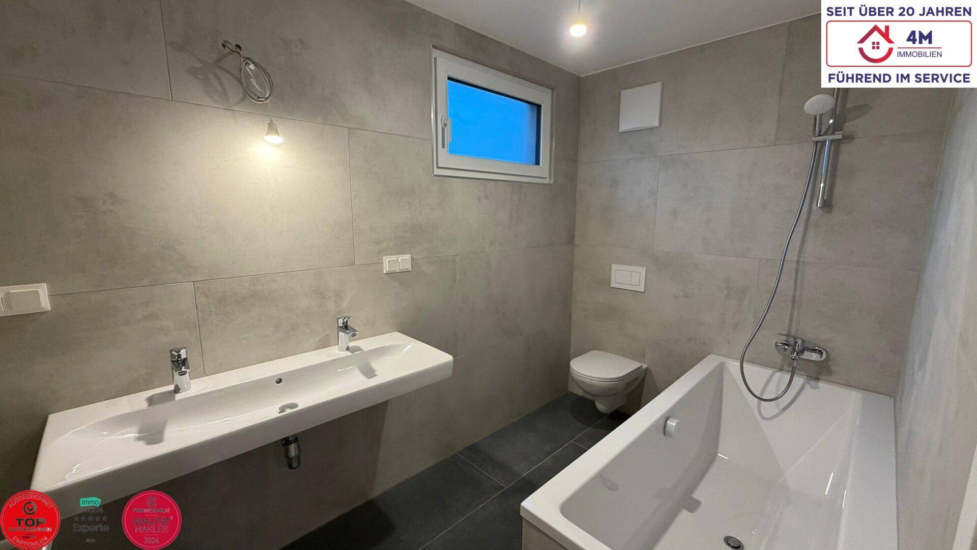 Geräumiges Badezimmer mit Doppelwaschbecken, Badewanne und Dusche, sowie einem Fenster.