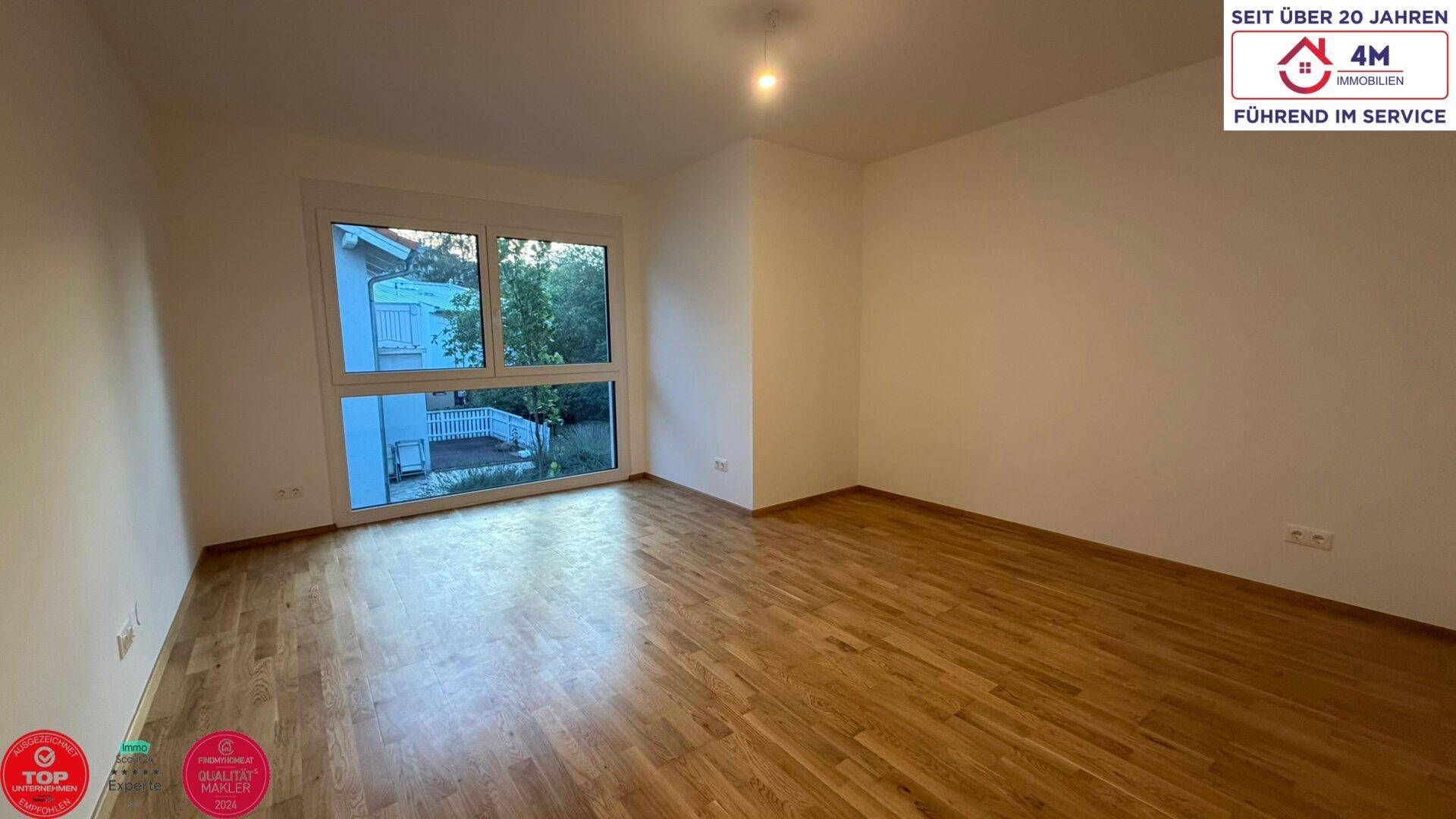 Freundliches Zimmer mit Holzboden und Blick ins Grüne, ideal als Schlaf- oder Arbeitszimmer.