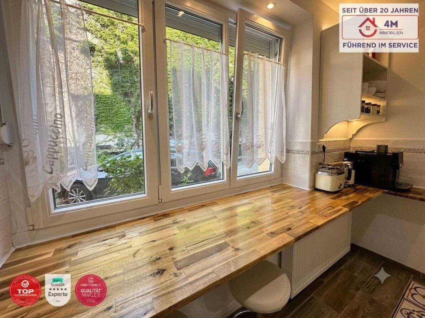 Helle Küche mit Holz-Arbeitsplatte und Blick ins Grüne durch das Fenster.