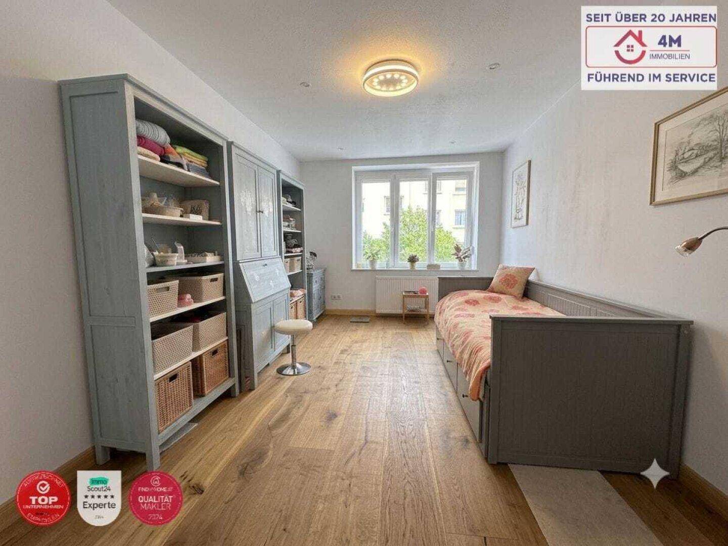 Helles Schlafzimmer mit Holzboden, Einzelbett und großem Bücherregal.