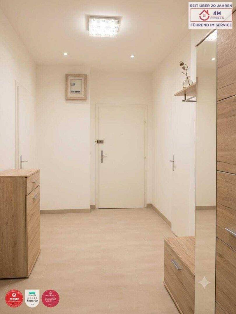 Heller Eingangsbereich mit Fliesenboden, Garderobe und einem großen Spiegel.