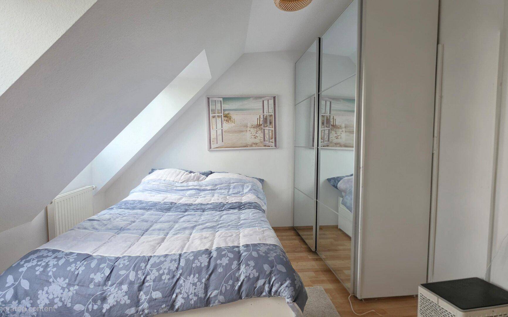Schlafzimmer im Dachgeschoss mit schrägen Wänden, Dachfenster und Spiegelschrank.