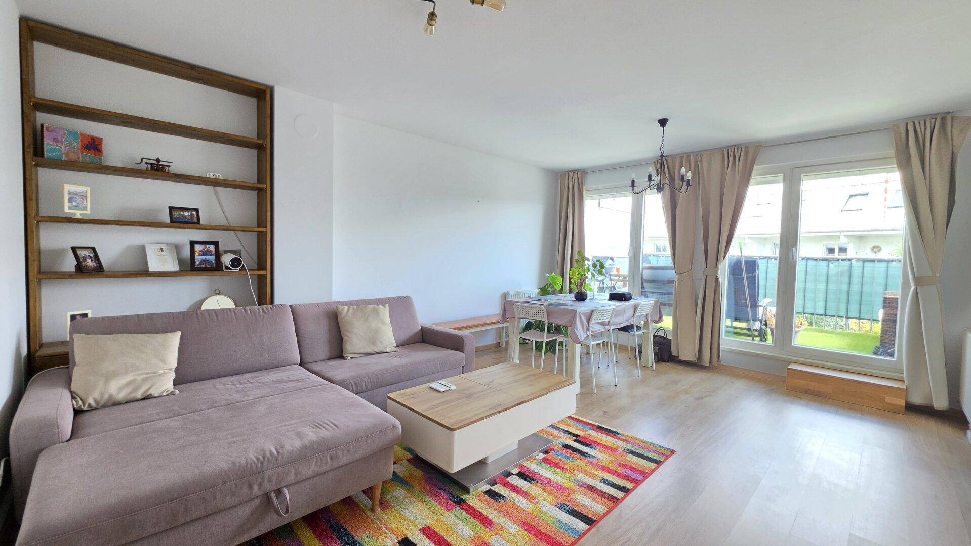 Geräumiger Wohnbereich mit Sofa, Regal und Essbereich, hell und modern eingerichtet.