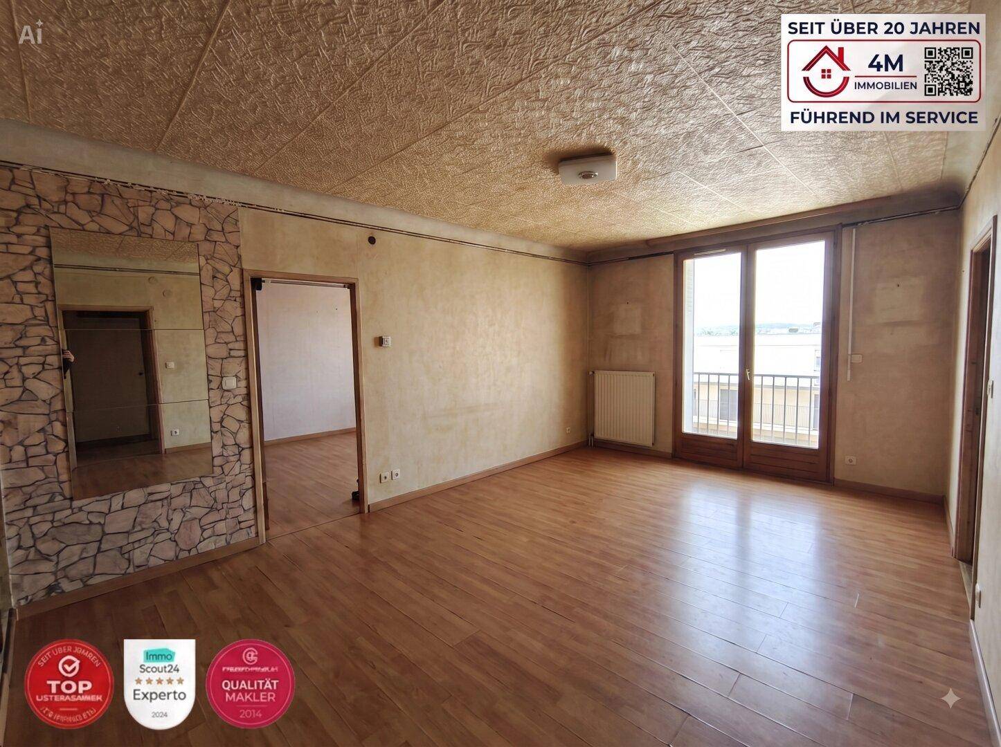 Geräumiges Wohnzimmer mit Holzboden, strukturierten Wänden und Zugang zu einem kleinen Balkon.