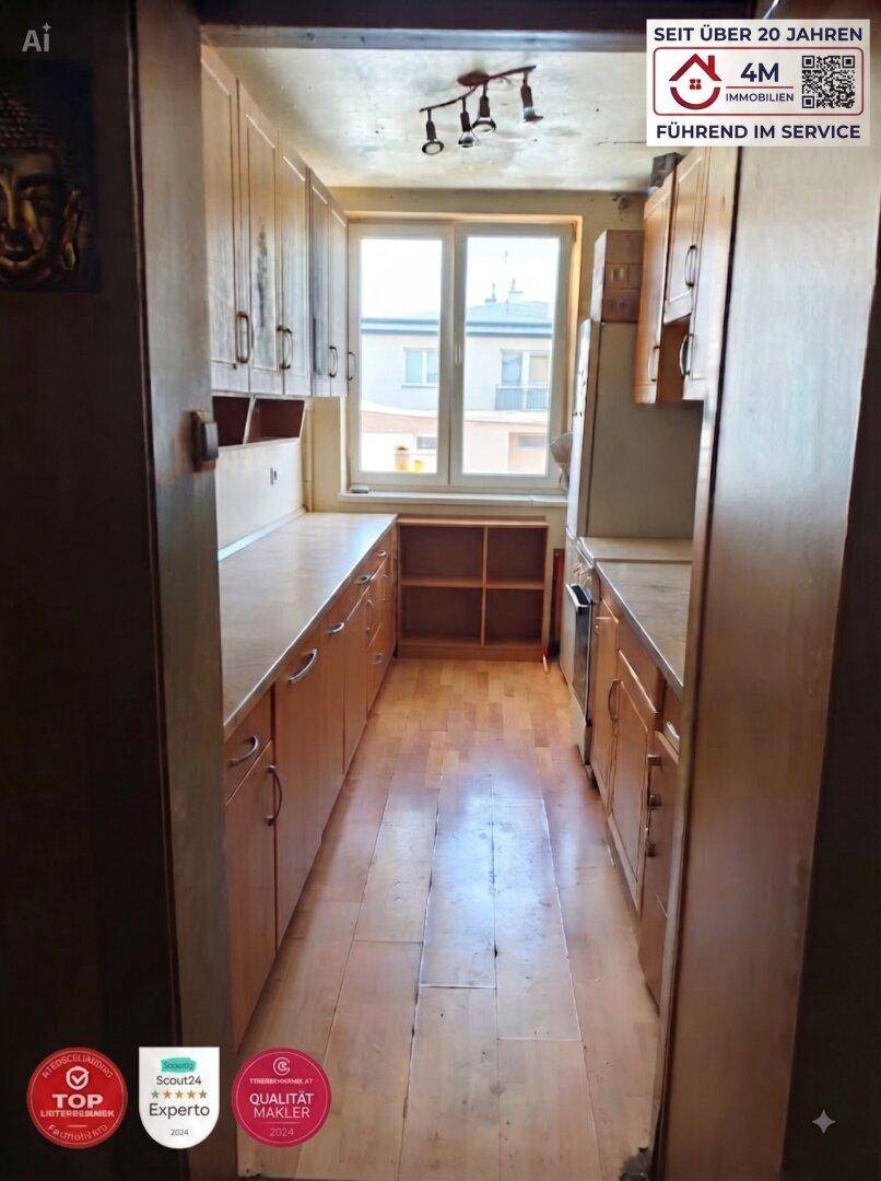 Helle Küche mit Holzschränken, Arbeitsplatten und einem Fenster mit Blick nach draußen.