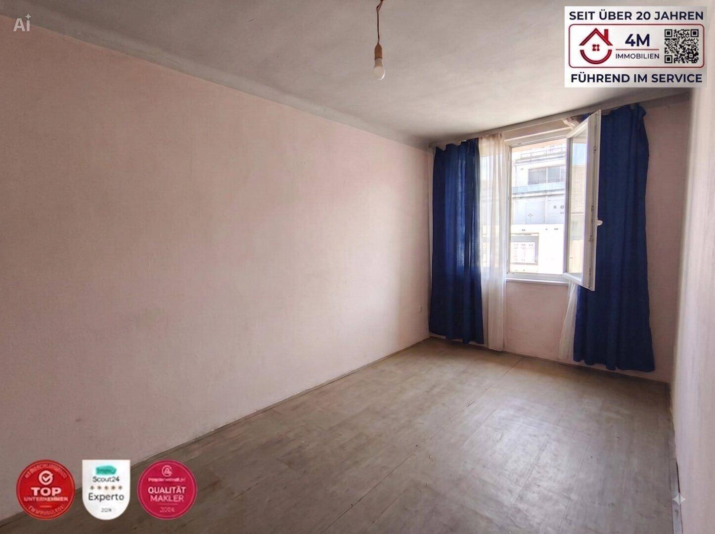Einfaches Schlafzimmer mit rosa Wänden, Holzboden und einem Fenster mit blauen Vorhängen.
