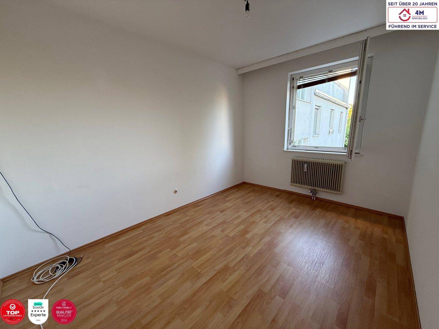 Helles Schlafzimmer mit Laminatboden und einem geöffneten Fenster für frische Luft.