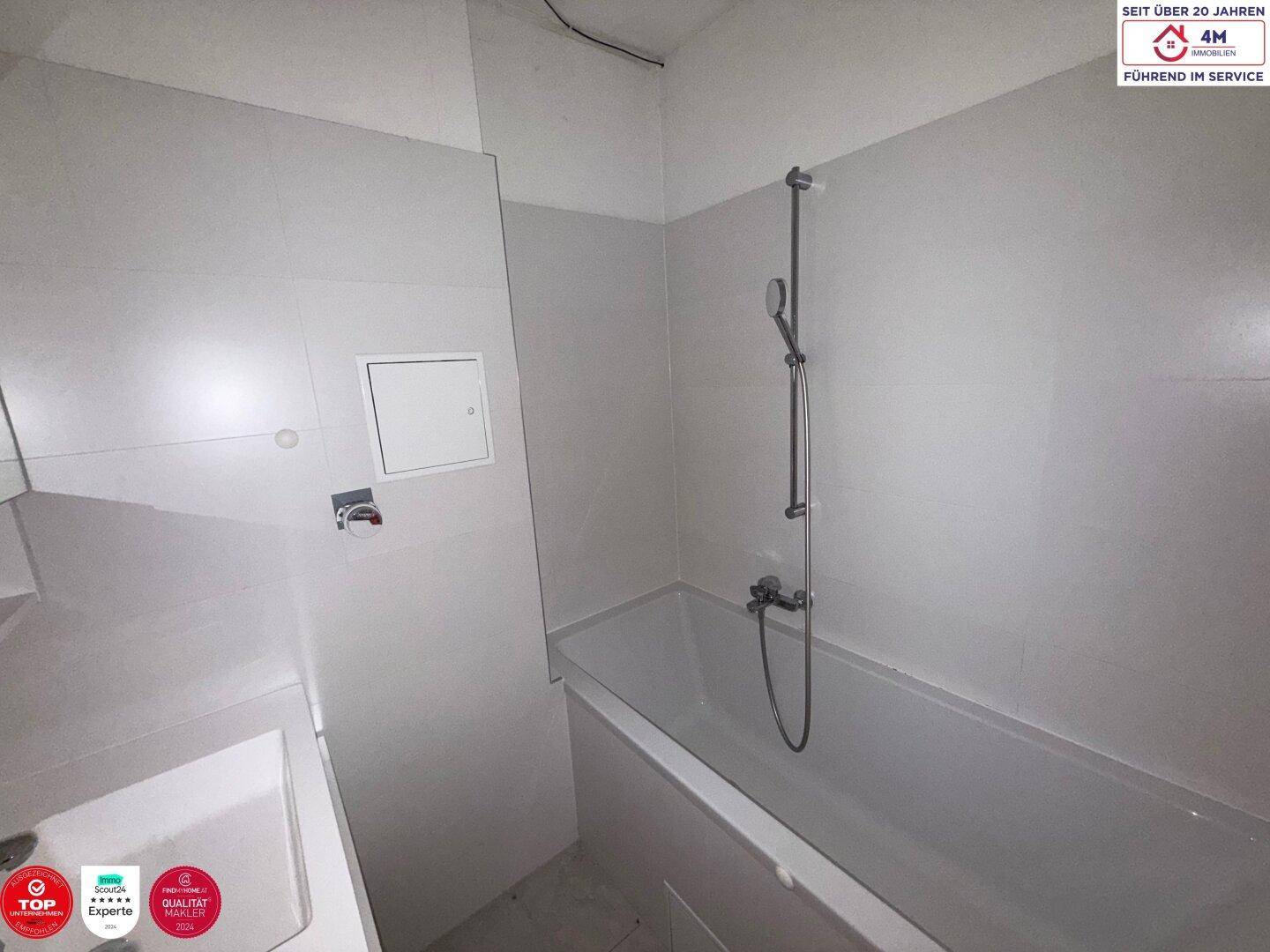 Badezimmer mit Badewanne und Duscharmatur, in schlichtem, funktionalem Design.