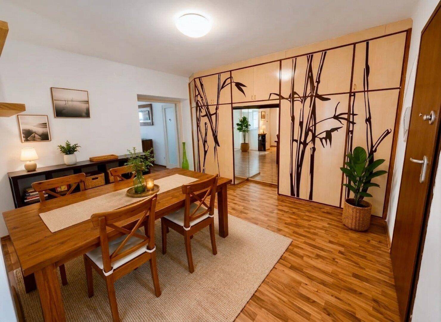 Esszimmer mit Holztisch, passenden Stühlen und dekorativer Bambuswand.