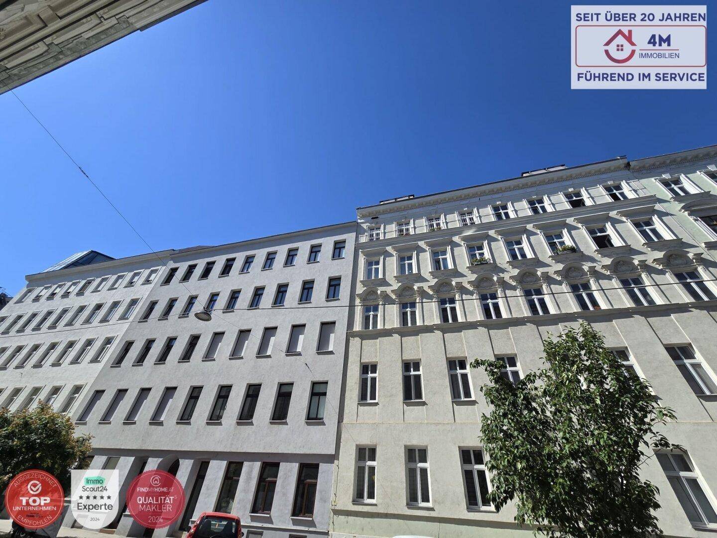 Fassade eines Mehrfamilienhauses mit vielen Fenstern unter blauem Himmel.
