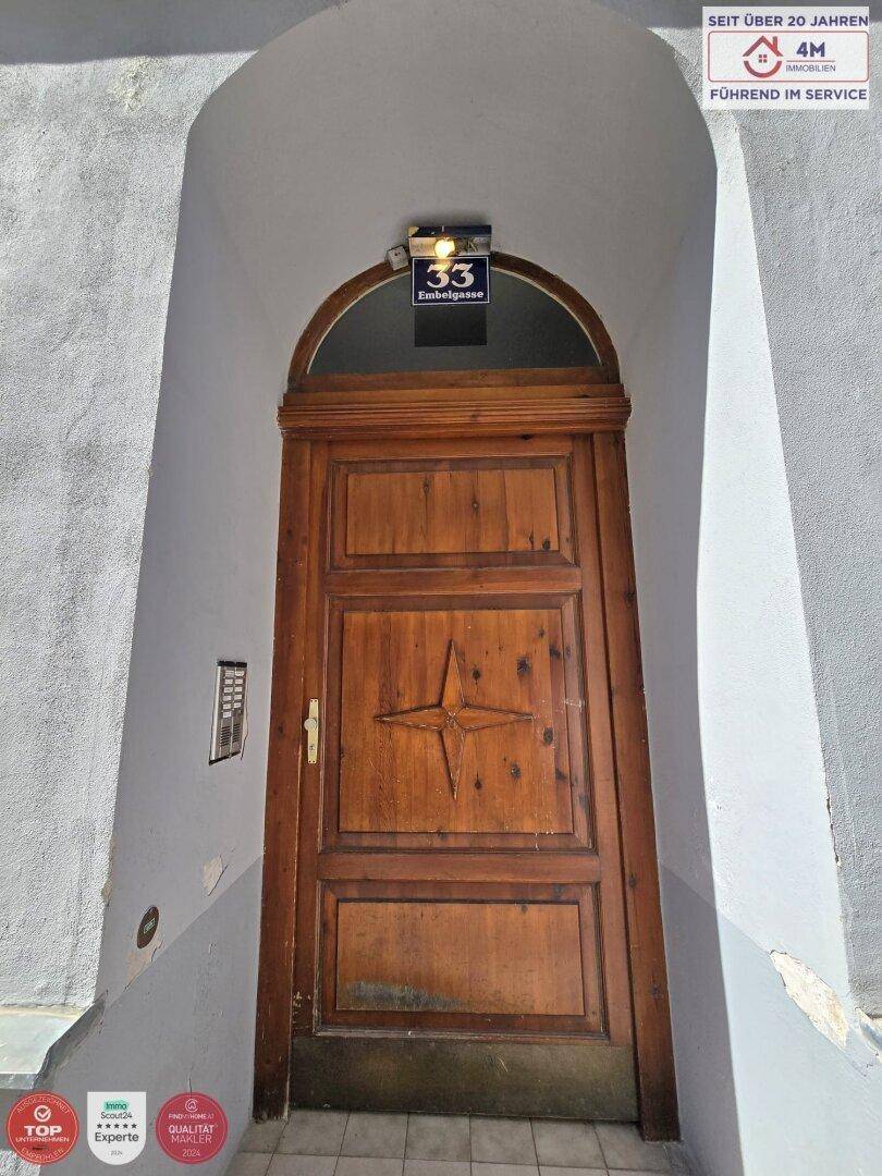 Historische Holztür mit Hausnummer und Gegensprechanlage als Eingangsbereich.