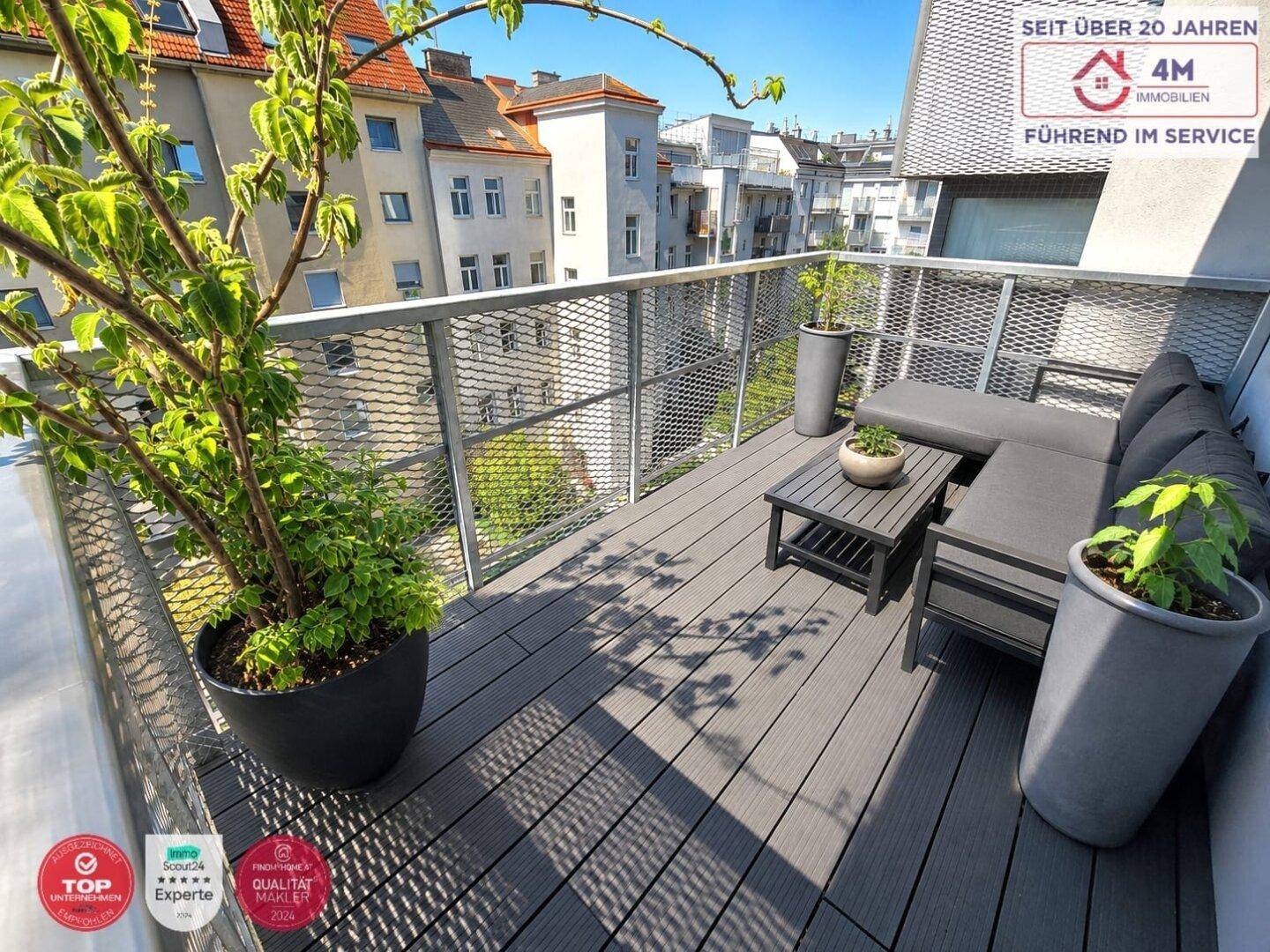 Möblierte Dachterrasse mit Holzboden und Blick auf die umliegenden Gebäude.