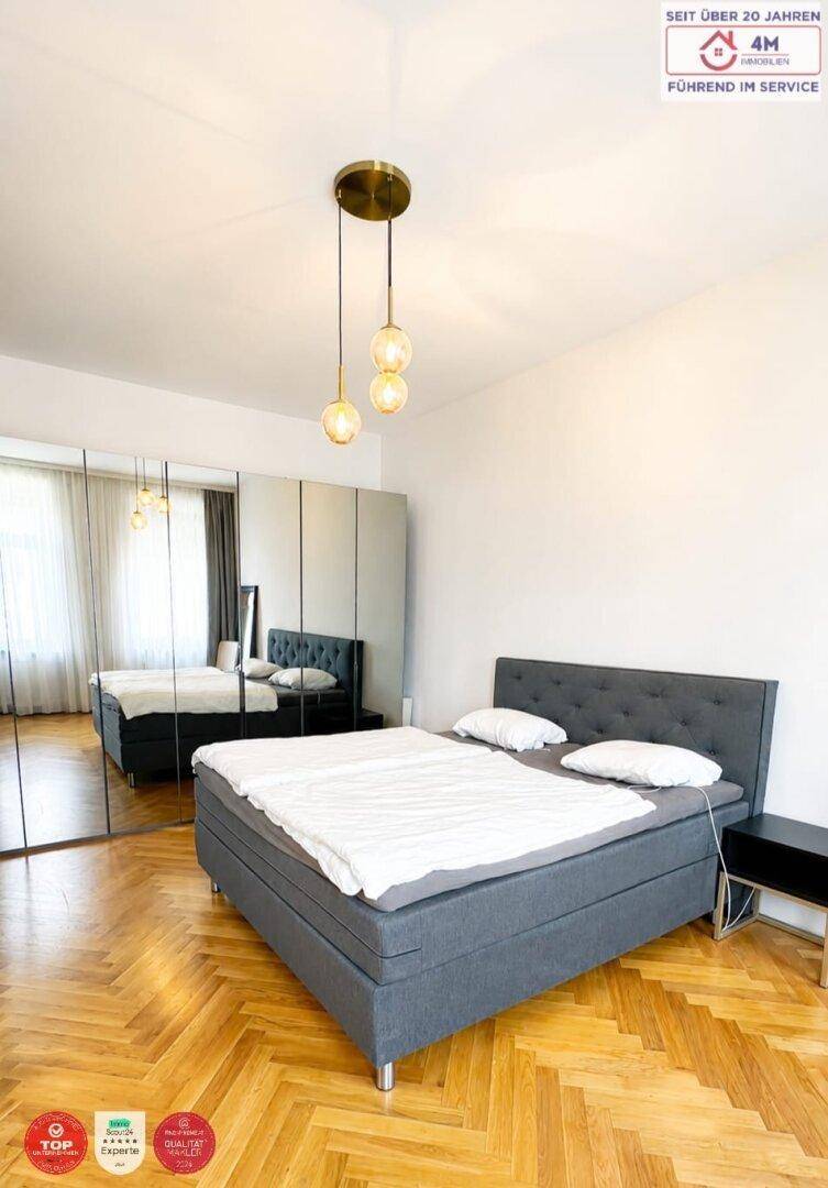 Schlafzimmer mit großem Bett, Spiegelschränken und Fischgrätparkett.