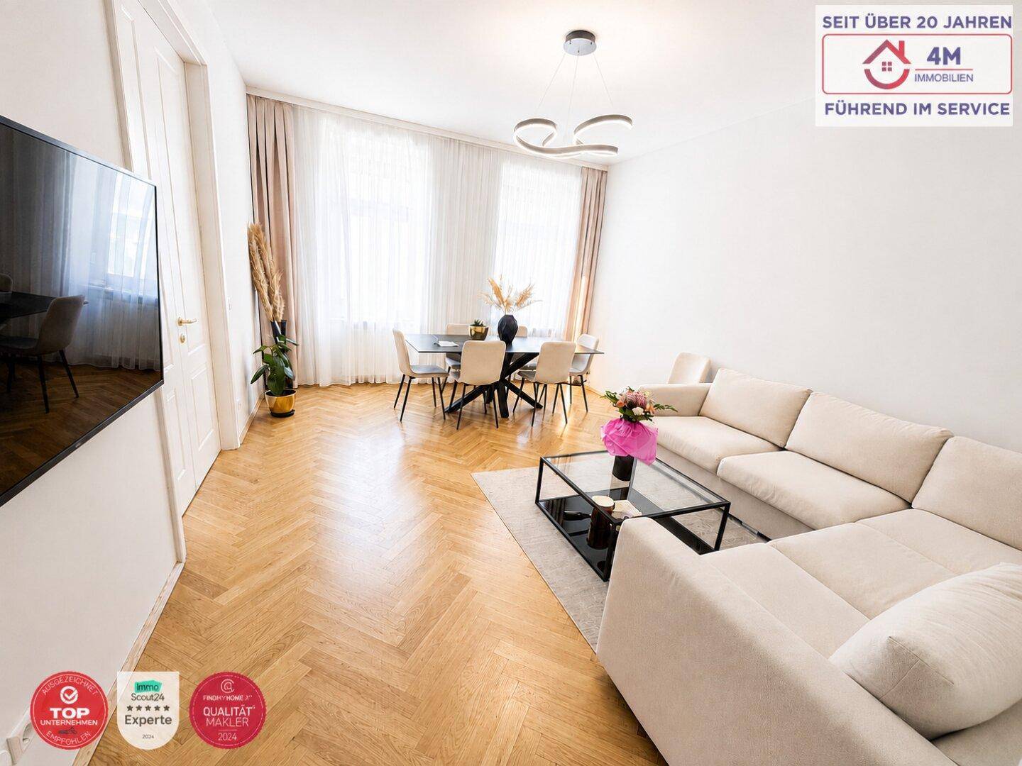 Geräumiger Wohn-Essbereich mit Fischgrätparkett, beigem Sofa und Esstisch.