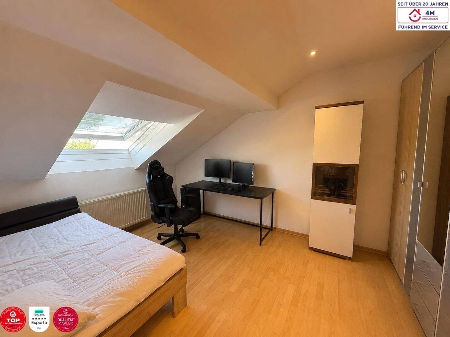Helles Schlafzimmer im Dachgeschoss mit Schreibtisch, Gaming-Stuhl und Dachfenster, ideal für Home-Office.