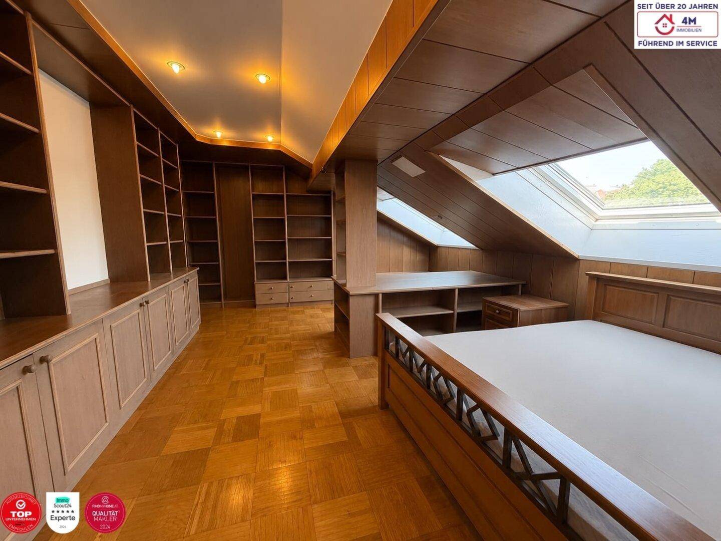Geräumiges Schlafzimmer im Dachgeschoss mit Einbauschränken, Holzboden und Dachfenstern, die viel Licht spenden.