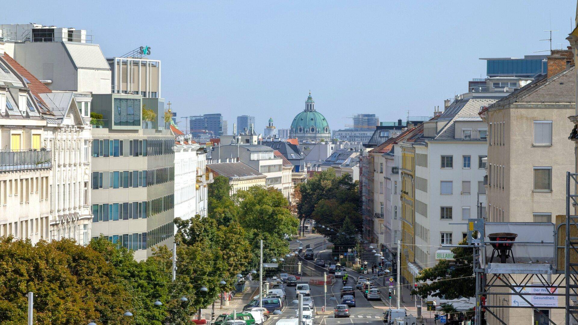 Panoramablick über eine belebte Stadtstraße mit Gebäuden und einer markanten Kuppel in der Ferne.