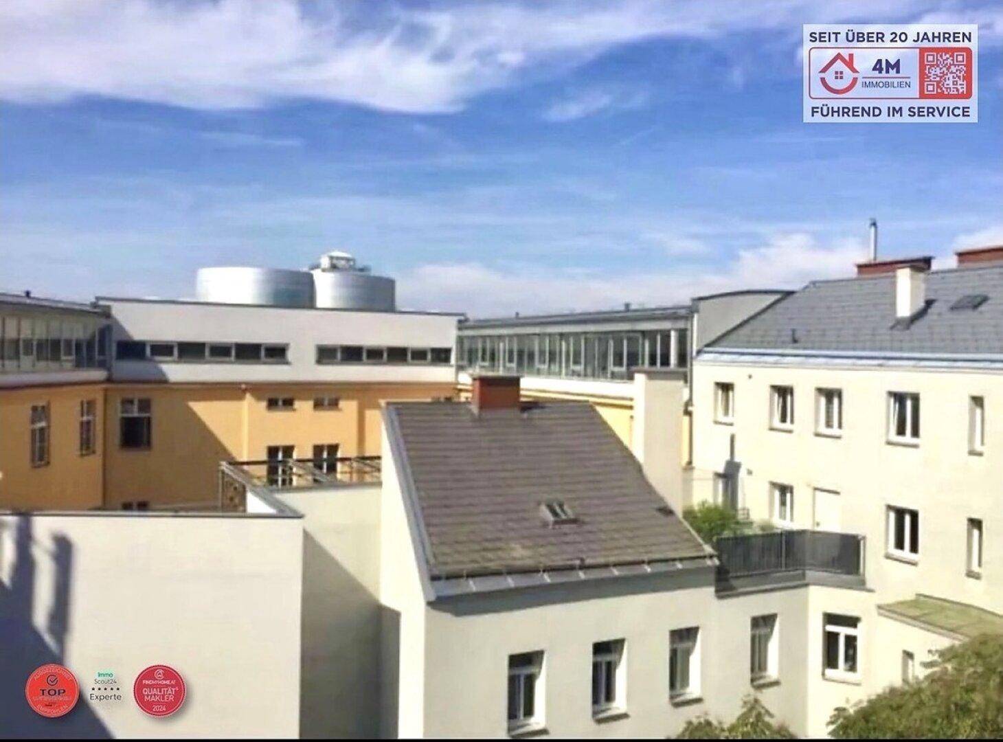 Blick über die Dächer der Stadt mit verschiedenen Gebäuden und einem blauen Himmel.