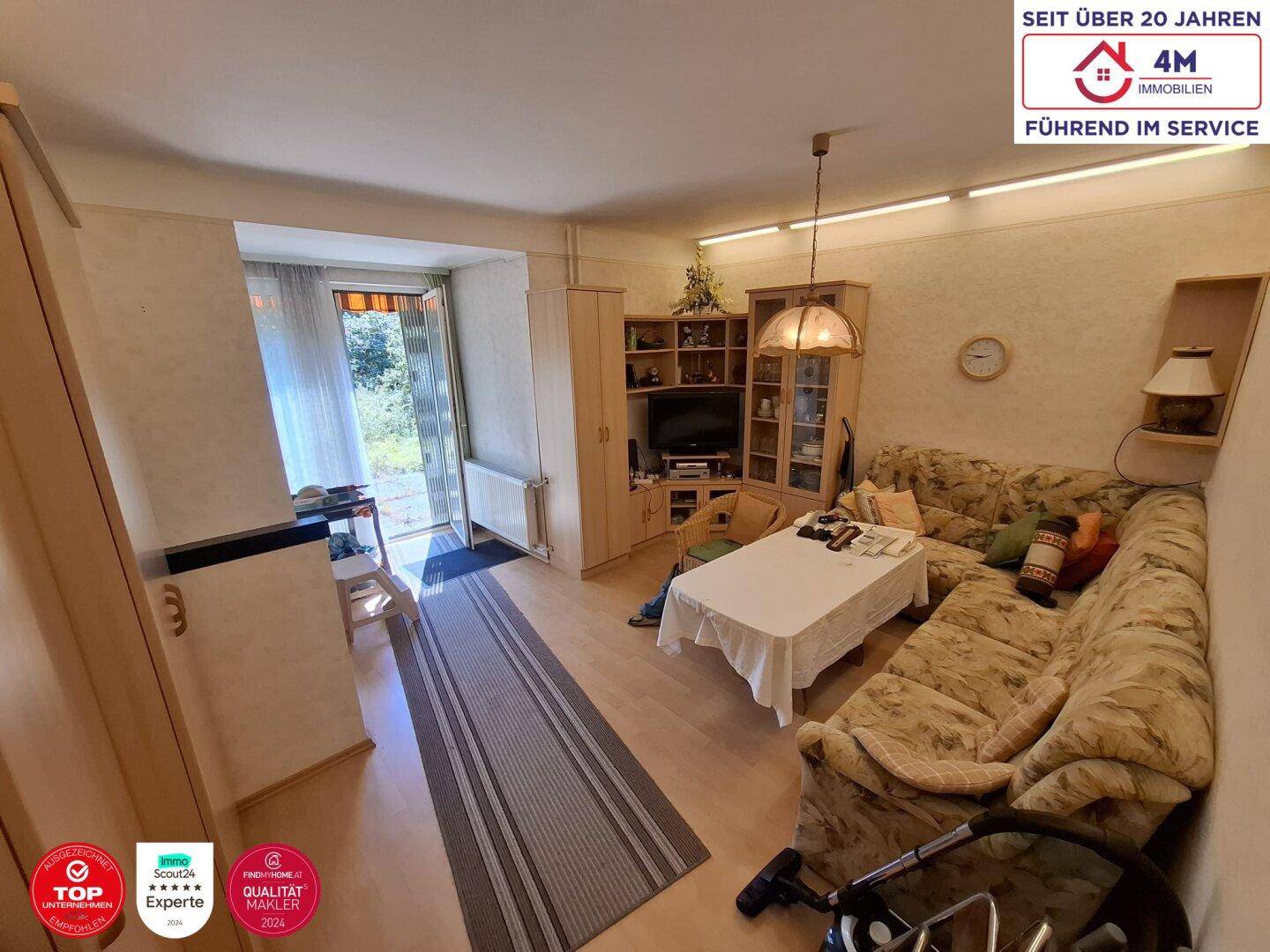 Wohnzimmer mit bequemer Eckcouch, kleinem Tisch und Zugang zu einem Außenbereich.