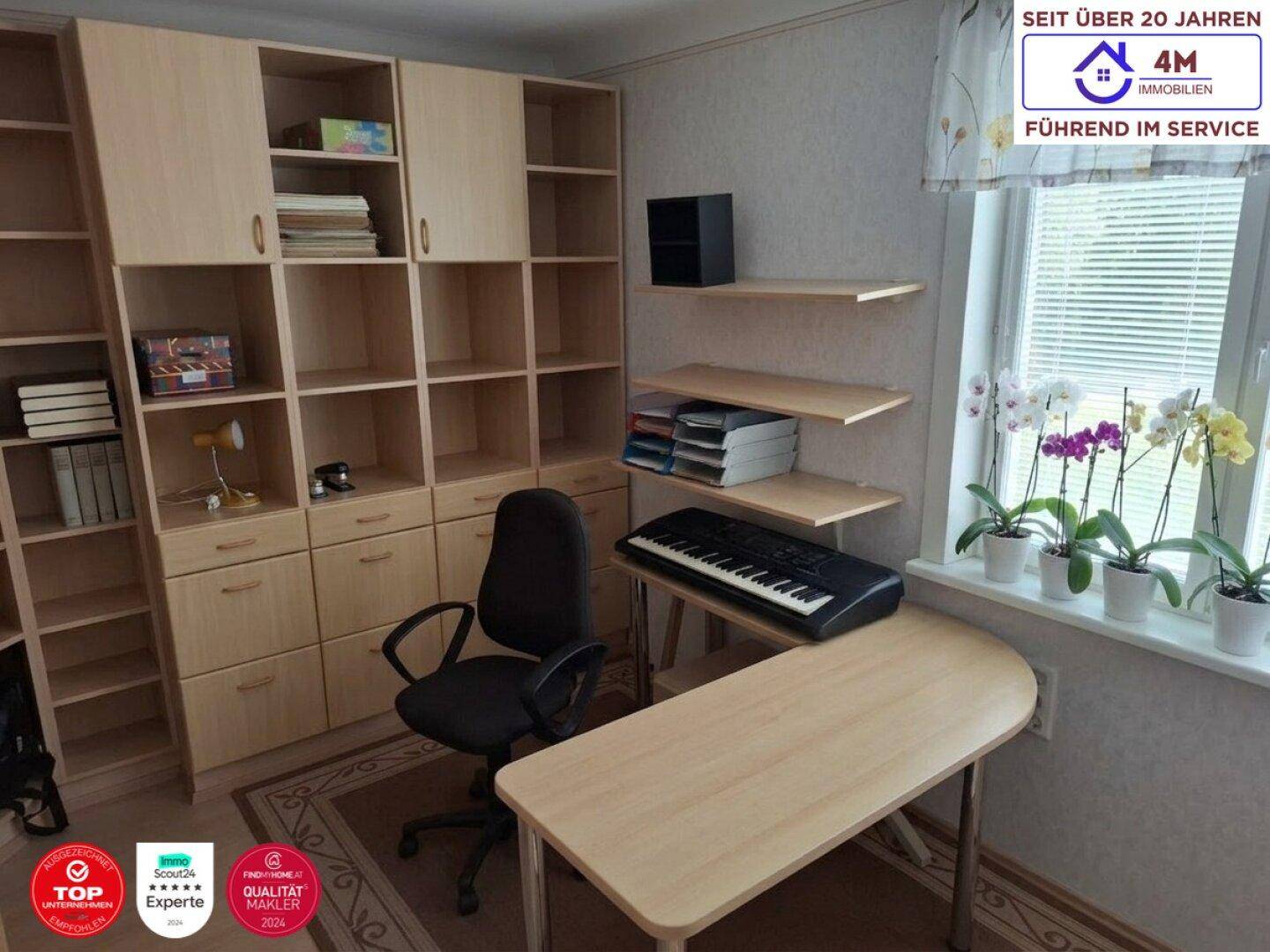 Arbeitszimmer mit Schreibtisch, Bürostuhl und großen Regalsystemen, hell durch Fenster.