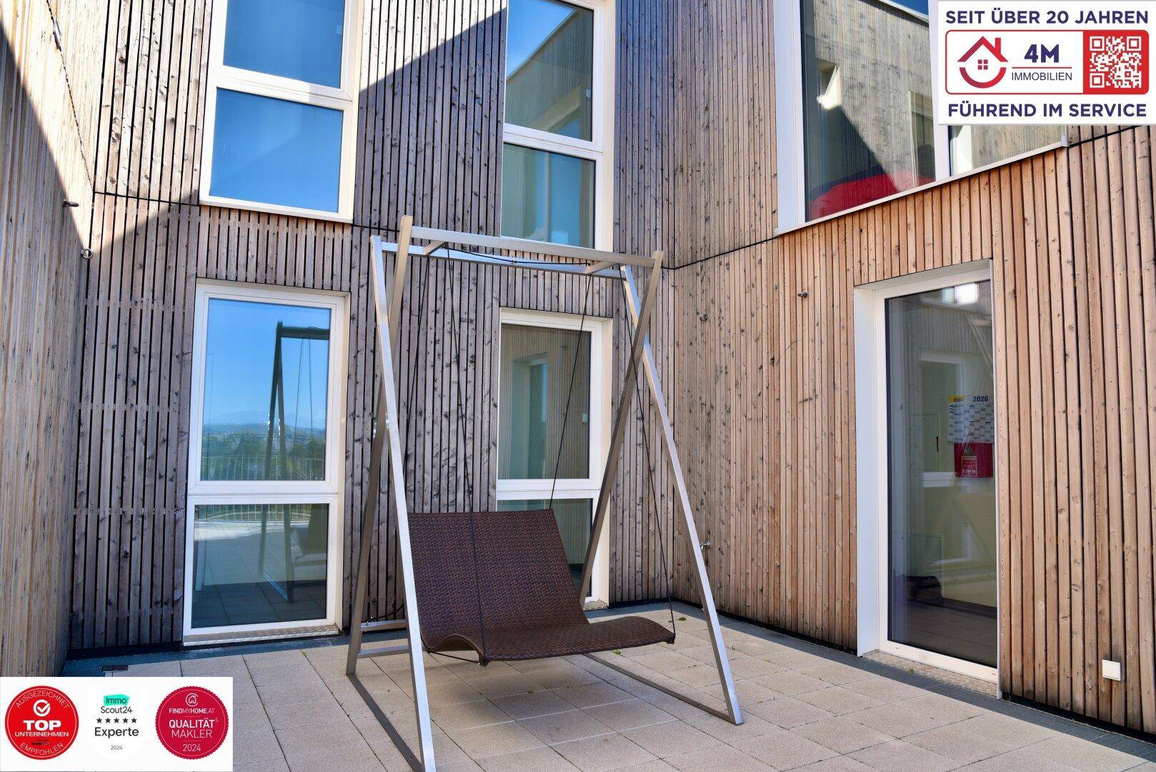 Moderne Terrasse mit einer Schaukelbank und Holzfassade, perfekt für entspannte Stunden im Freien.