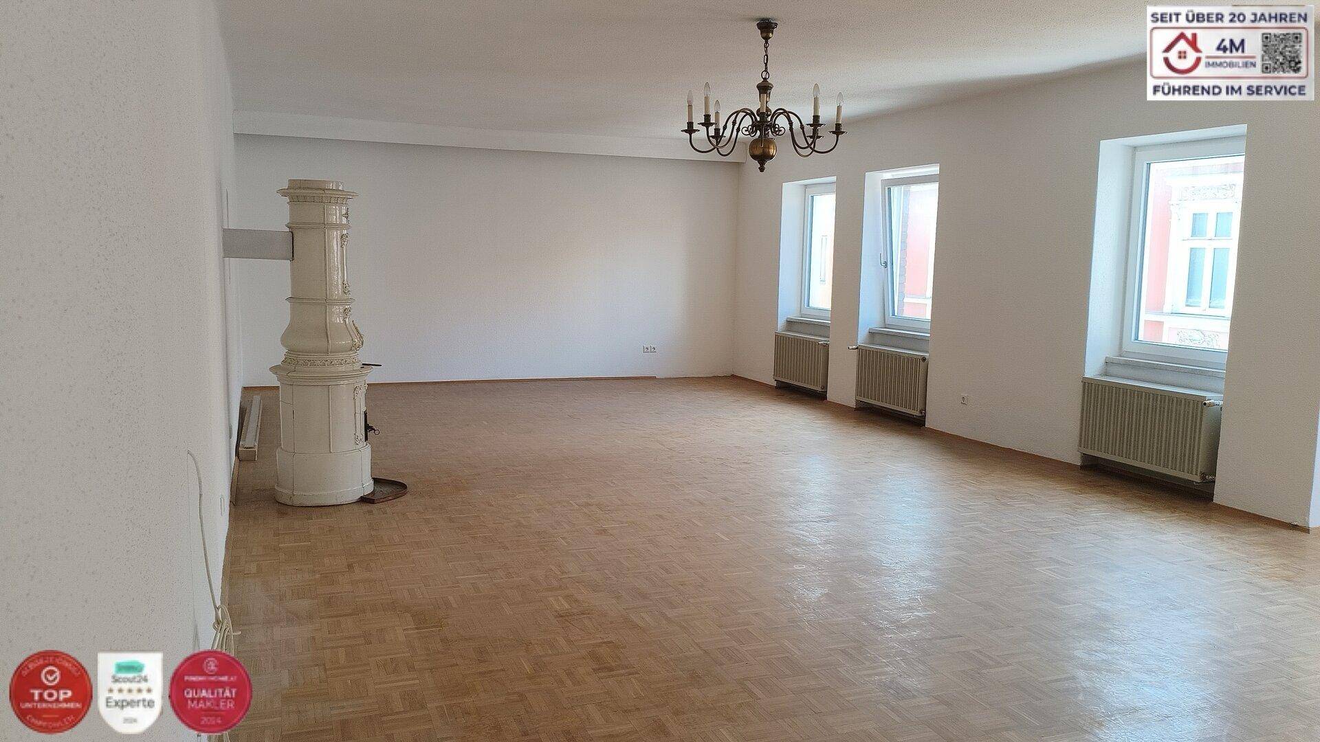 Helles Wohnzimmer mit traditionellem Kachelofen und Fischgrätparkettboden.