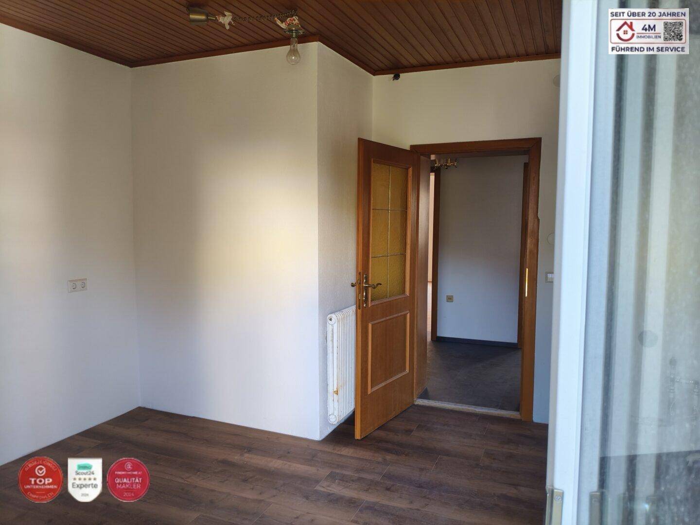 Heller Flur mit Holztür, Holzdecke und modernem Laminatboden.