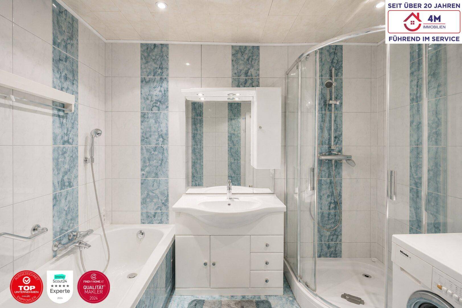 Badezimmer mit Badewanne, Duschkabine und Waschbecken in hellblauer Fliesenoptik.
