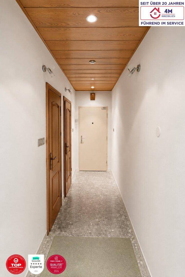 Heller Flur mit Holzdecke, Einbaustrahlern und Zugang zu verschiedenen Räumen.