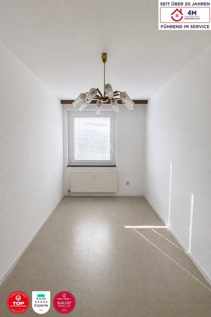 Leerer Raum mit weiß gestrichenen Wänden, Fenster und einem Heizkörper darunter.