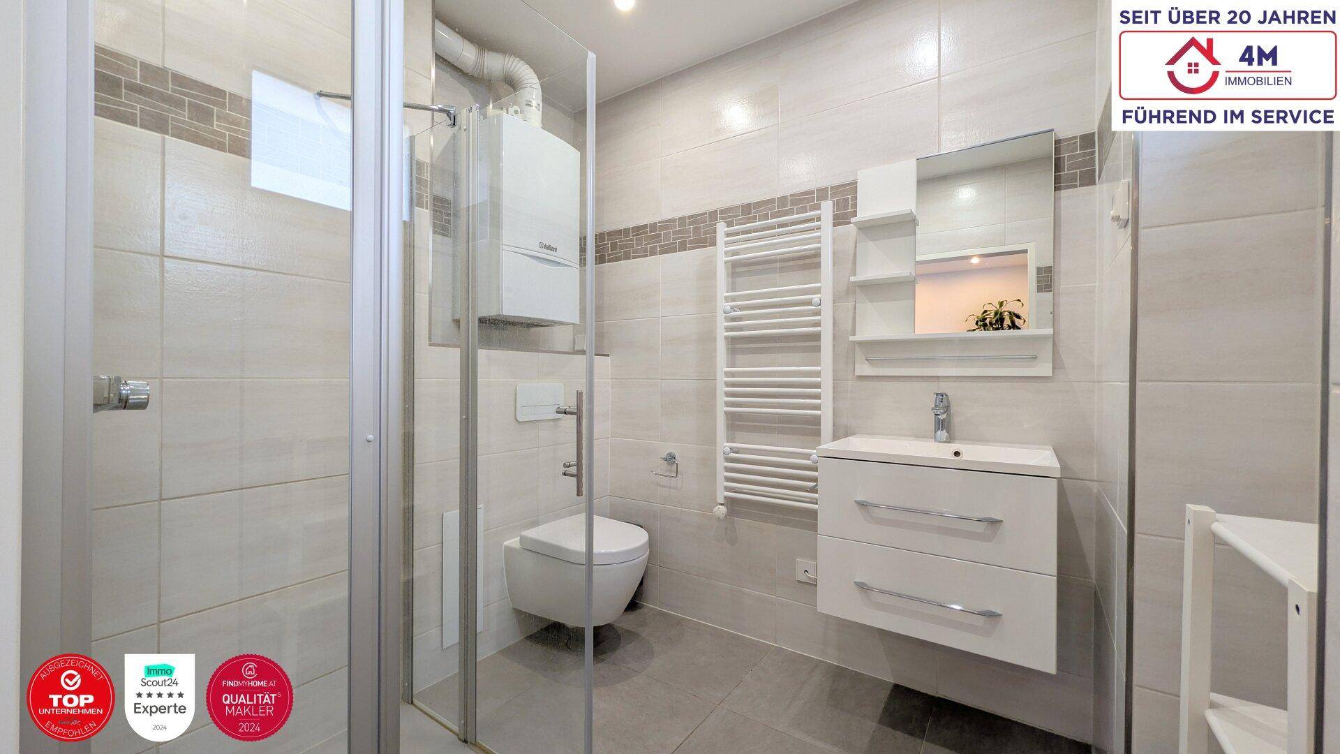 Modernes Badezimmer mit Duschkabine, Hänge-WC und beheiztem Handtuchhalter.